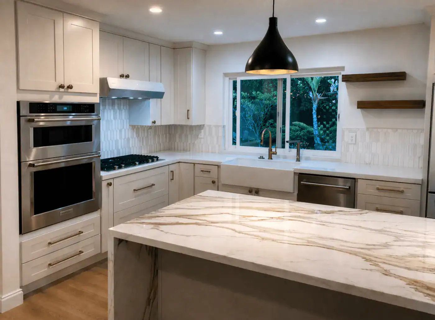 Remodeled Santa Monica kitchen with a porcelain waterfall island, cream shaker cabinets, double wall oven and farmhouse sink